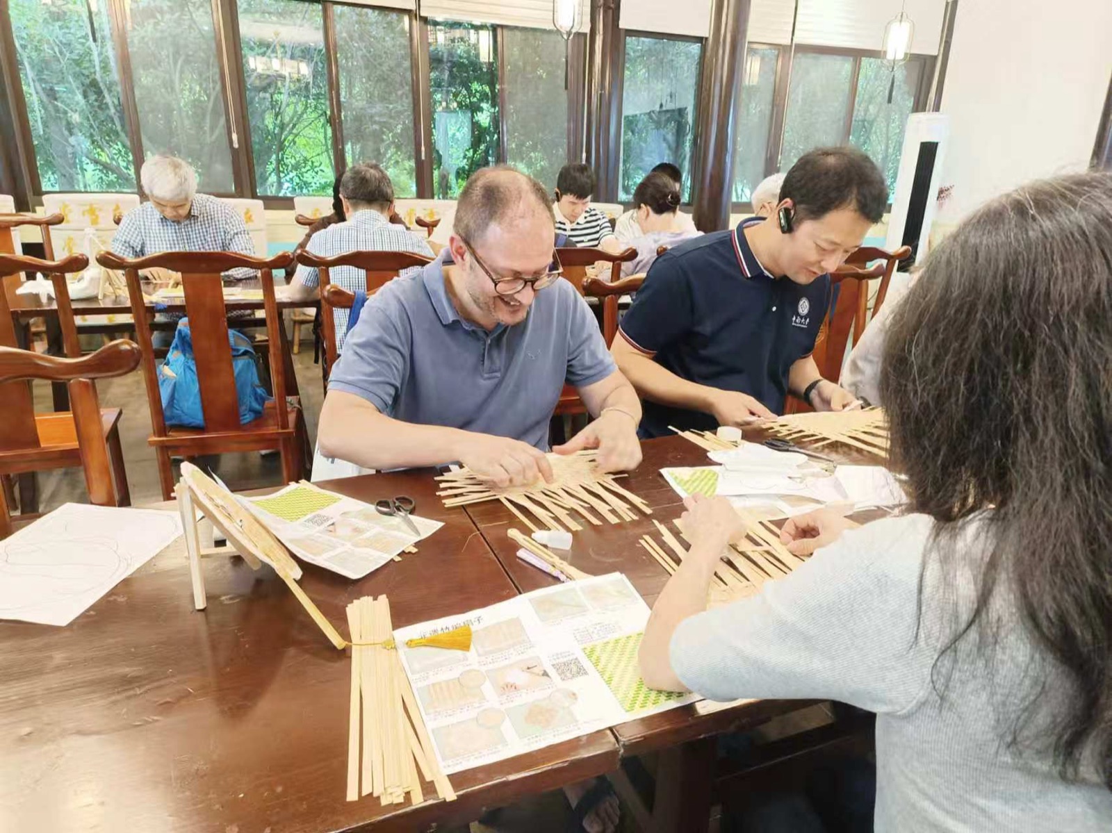 Visitors weaving thin bamboo strips into patterns at a Jiangnan workshop