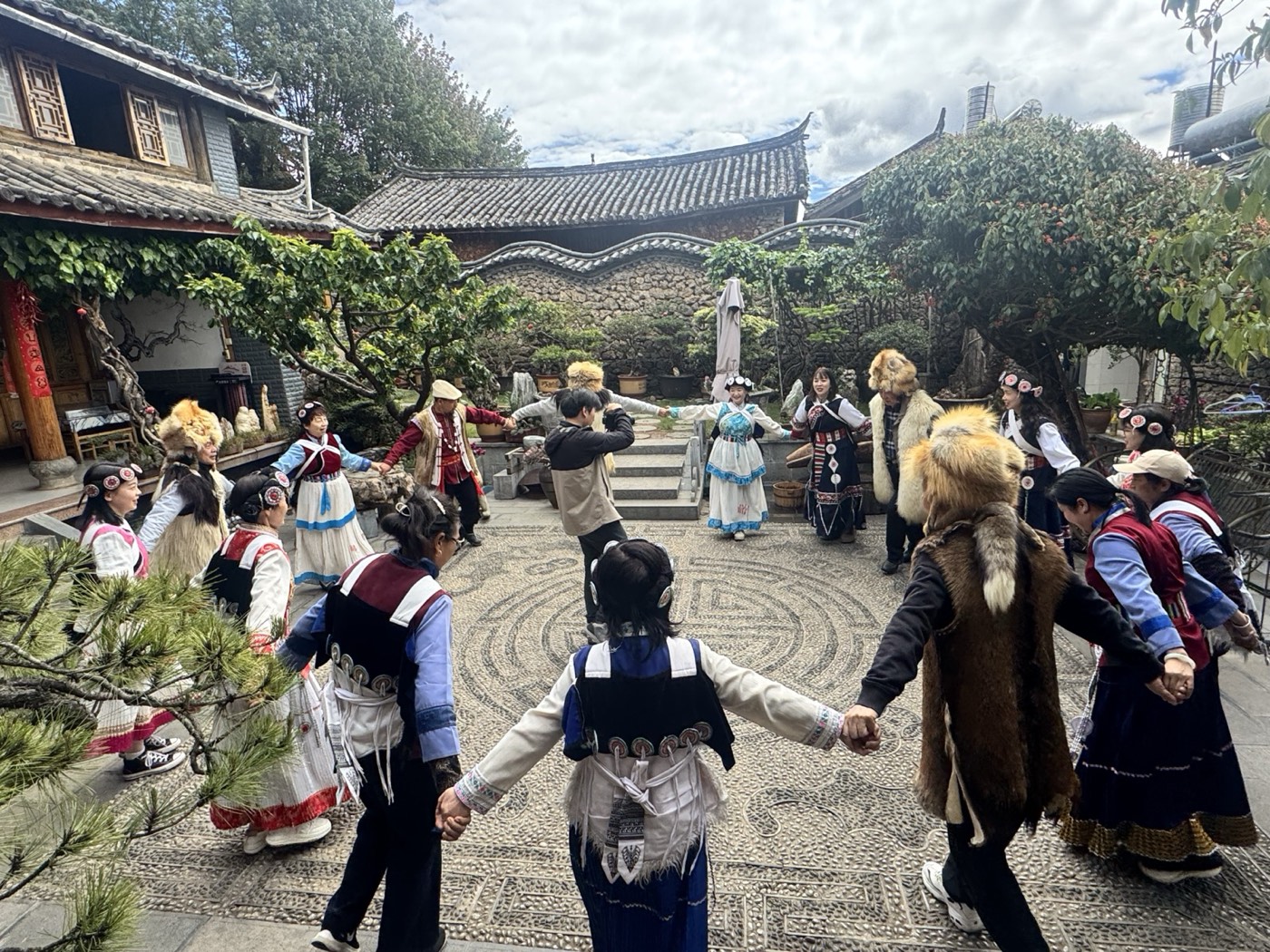 Naxi people in traditional dress dancing in a Lijiang courtyard